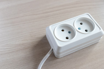 Electrical extension socket with cable on wooden background. Place for your text. Concept of saving electric energy, safety.Side view