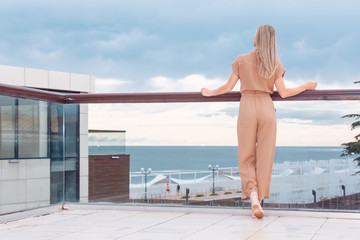 Rear view of fit unidentified young woman tourist admiring magnificent view from hotel terrace to...