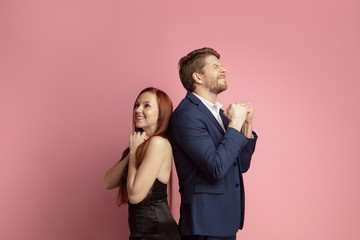 Dreaming together. Valentine's day celebration, happy caucasian couple isolated on coral studio background. Concept of human emotions, facial expression, love, relations, romantic holidays.