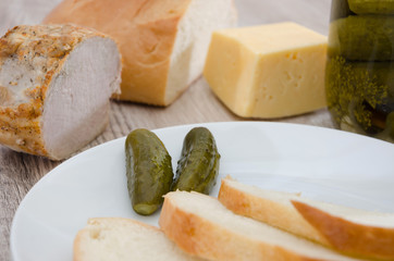 Ukrainian appetizer on a wooden table. Cucumbers, cheese, ham, bread.