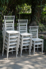 Fototapeta na wymiar Exquisite wooden white chairs one on the other in garden