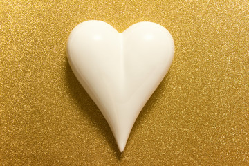 Large white porcelein heart on golden glitter sparkle backgound.