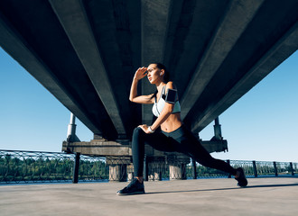 Sporty woman runner stretching legs for warming up before exercising and looking away