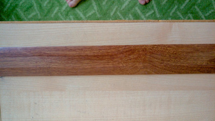 A dark brown plank sits on a light brown table