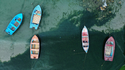 Aerial top down view of colorful fishing boats moored near the shore of Bolata cove on Black sea, Bulgaria. Turquoise water