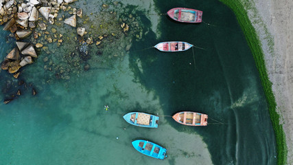 Top-down luchtfoto van kleurrijke vissersboten afgemeerd in de buurt van de oever van de baai van Bolata aan de Zwarte Zee, Bulgarije. Turkoois water