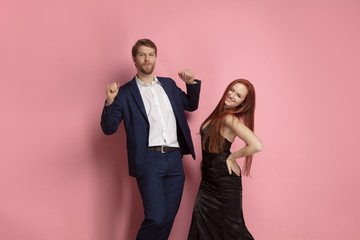 Laughting man and woman dancing together. Valentine's day celebration, happy caucasian couple on coral background. Concept of human emotions, facial expression, love, relations, romantic holidays.
