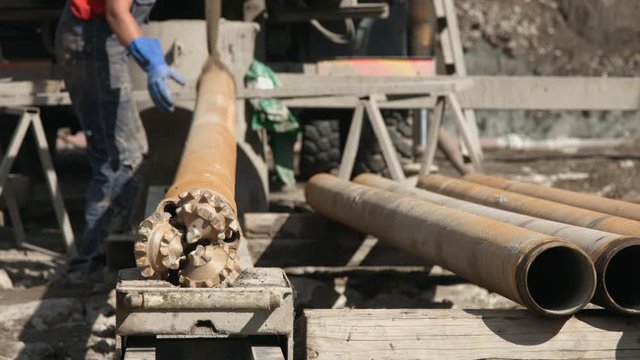 Worker attaching drilling rig pit pipe