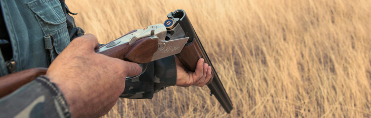 Hunting period, autumn season open. A hunter with a gun in his hands in hunting clothes in the...