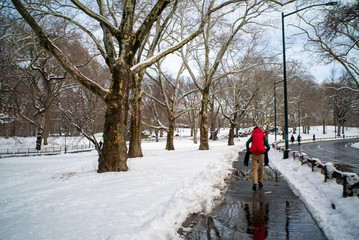 man carrying a woman on a road with waterpools in a winter snowy scenary 