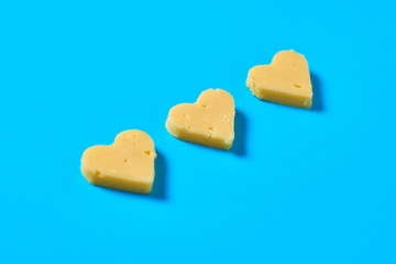 Three pieces of cheese in form of heart lies on blue desk on kitchen. Concept of Valentine's Day....