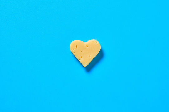 Piece of cheese in form of heart lies on blue desk on kitchen. Concept of Valentine's Day. Top view. Close-up