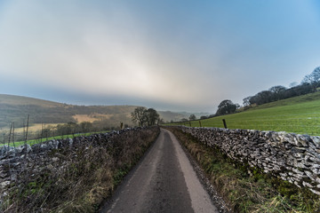 Fototapeta premium Road down the hills through the fields