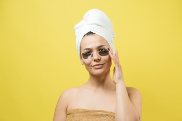 Young beautiful girl in a white towel on his head wears collagen gel patches under her eyes. Mask under eyes treatment face.