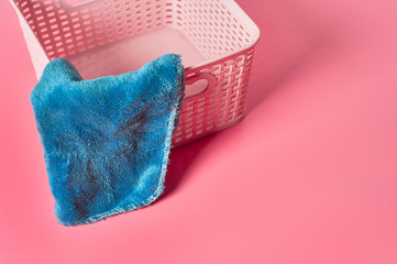 Empty plastic square basket for washing with blue soft towel lies on pink countertop in laundry. Space for text