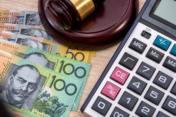 Money and justice. Wooden judge's gavel with colorful australian dollar banknotes close up