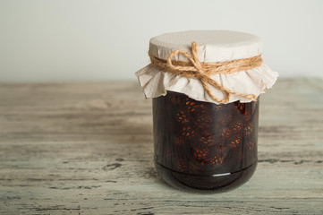 Traditional Trend Siberian dessert - young pine cones jam. Ukrainian cone jam in a jar on a light background close-up and copy space.