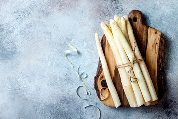 Bunch of raw white asparagus served on wooden board. Top view, copy space