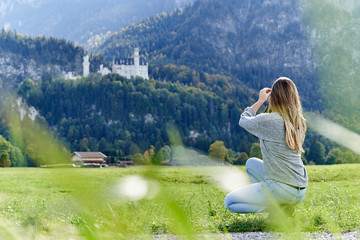 Tourist taking photos of the Neuschwanstein castle - obrazy, fototapety, plakaty