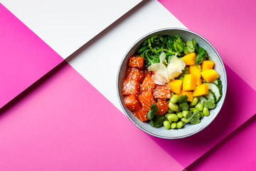 Hawaiian salmon poke bowl with seaweed, avocado, edamame, mango and pickled ginger. Top view,...