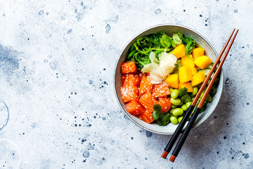 Hawaiian salmon poke bowl with seaweed, avocado, edamame, mango and pickled ginger. Top view,...