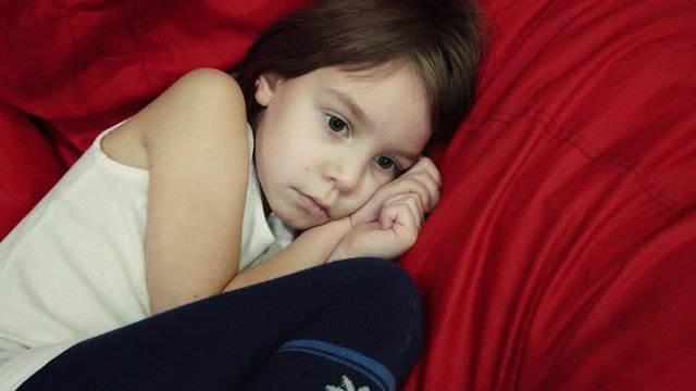 A charming, cute little child, a blonde girl, lies in a soft bag. Soft bag with filler as a comfortable and cozy bed.
