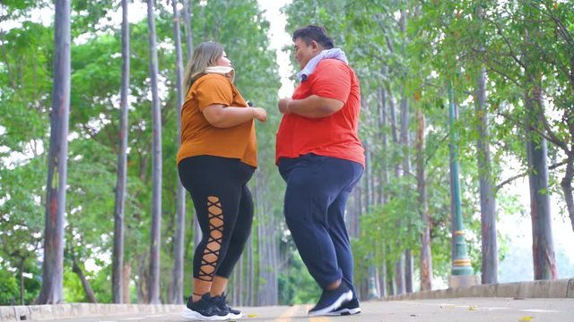 JAKARTA, Indonesia - January 11, 2020: Happy overweight couple doing exercise by running in a place together at the park. Shot in 4k resolution