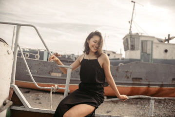 Obraz premium Woman in black dress on beach with broken ships