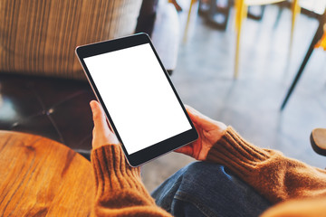Mockup image of a woman sitting and holding black tablet pc with blank white desktop screen