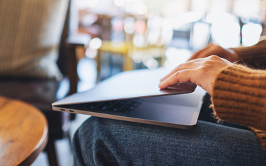 Closeup image of a woman close and open a laptop computer after finished using it