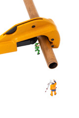 Miniature scale model construction workers with a copper pipe and a pipe cutter isolated.  Plumbing industry concept