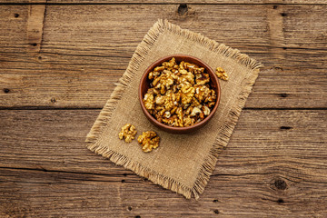 Fototapeta na wymiar Sprinkled walnuts in ceramic bowl. Natural organic snack, healthy eating concept