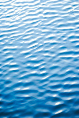 Ripples on the surface of the water in shades of the color of the year classic blue. Blurred texture with gradient for background or backdrop.