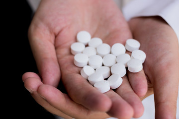 Close-up of man holding pills in hand.