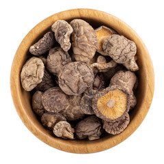 Dried shiitake mushrooms  in wooden bowl isolated on white background. Top view.