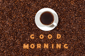 Naklejki  Biały kubek do kawy i napis Good Morning z literek herbatników na ciemnym tle ziaren kawy