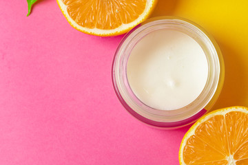 Cosmetic bottle with sliced citrus fruits on bright pink background