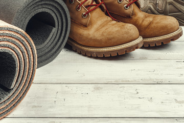 Hiking boots with travel accessories on grunge background