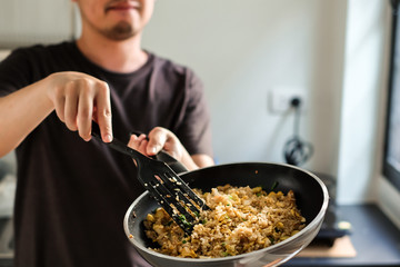 man cooking homemade asian fried rice with eggs  in a kitchen