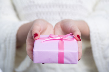 girl holding a present in hands, woman with gift box wrapped in decorative pink paper on white isolated background, concept winter holiday
