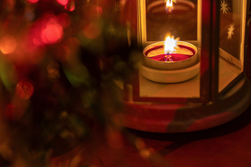 Candle in a lamp with copy space on a colored background with bokeh. Focus with shallow depth of field.
