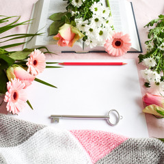 Lifestyle flat lay: Bouquet of wild flowers on open book white table background. Drawing, painting, colored pencils, artist. Pink coral rose tone. Top view. Mock-up. Copy space.
