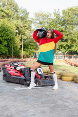 happy brunette women wining the karting race. oung blonde girl in red sports suit posing in summer on a kart track