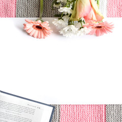 Lifestyle flat lay: Bouquet of wild flowers on open book white table background. Drawing, painting, colored pencils, artist. Pink coral rose tone. Top view. Mock-up. Copy space.