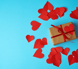 a rectangular box is wrapped in brown paper and tied with a red thin silk ribbon