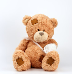 large beige teddy bear with patches sits on a white background