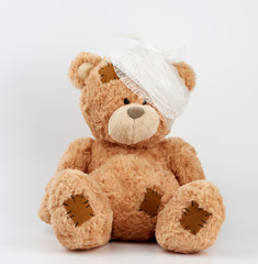 big teddy bear with a bandaged head in a white medical bandage on a white background