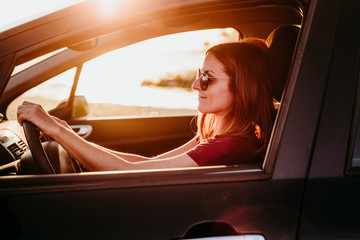 Naklejka premium young woman driving a car at sunset. travel concept