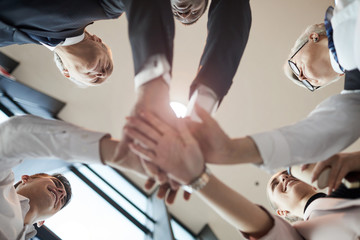 Low angle view of business team holding hands and cooperating with each other during team work at office