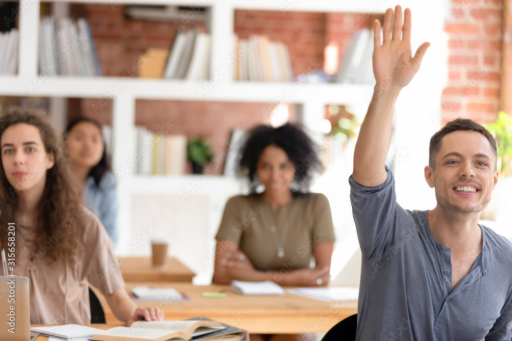 Wall mural Motivated male student ask hand asking question at lesson